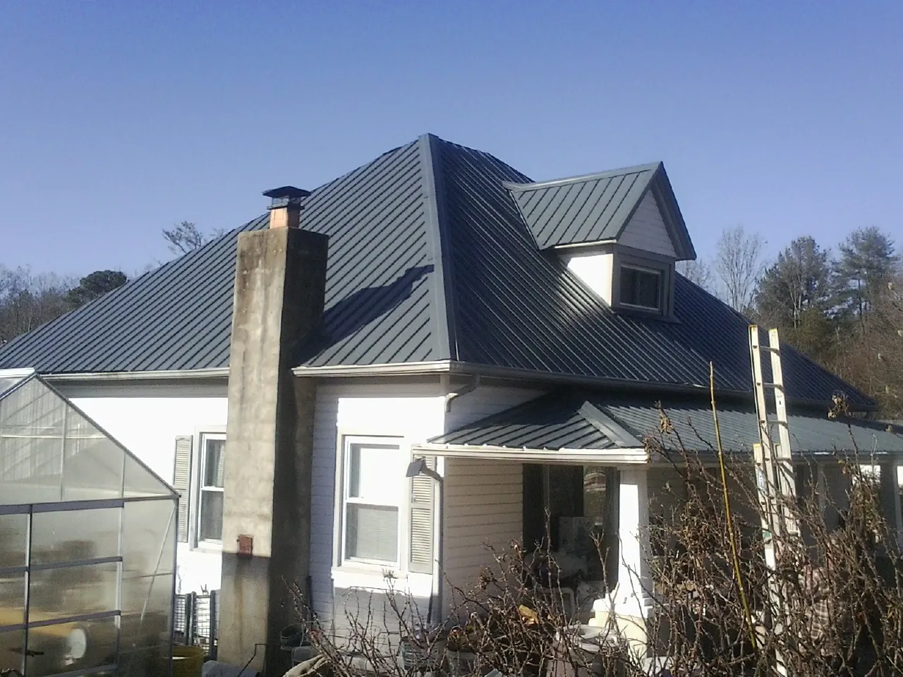 Dark blue standing seam metal roof on a white farmhouse with dormer — Slate & Tile Roof Repair by Roofing Brothers in New London